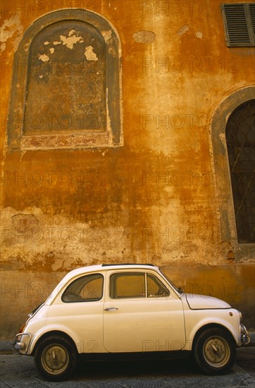 ITALY, Tuscany, Florence, White Fiat 50 parked outside old building with faded ochre coloured plaster wall.
