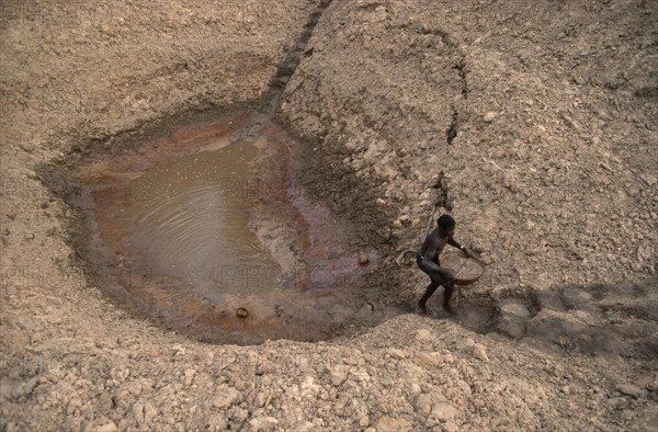 20074005 MALI  Water Man carrying bowl of water up steps from waterhole to irrigate his onions.