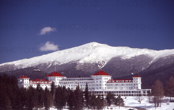 USA, New Hampshire, Bretton Woods, "Mount Washington Hotel, large white building with red roof, snow peaked mountain behind."