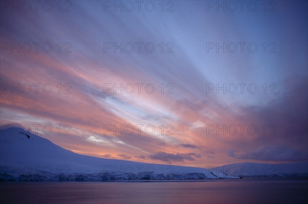 ANTARCTICA, Port Lockroy, Orange sunset over glacial landscape.