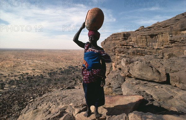 20074822 MALI Bandiagara Escarpment Water Dogon woman returning to Tirelli village with empty pot carried on her head.