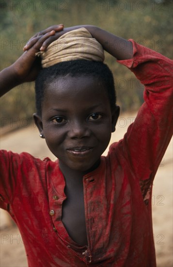 GHANA, Children, Portrait of young girl with coiled cloth on her head for carrying water pot.