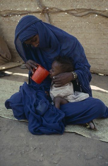 SUDAN, North East, Mother helping her malnourished child to drink at Sinkat feeding centre.