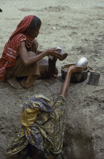 ETHIOPIA, Water, Women filling water vessels at well.