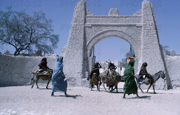 NIGER, Architecture, Town gate with women walking or riding donkeys past below.