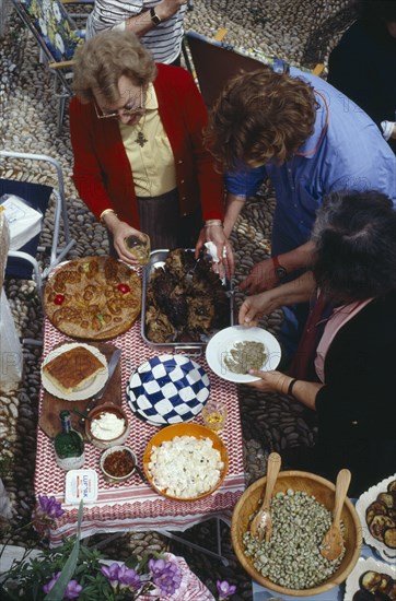 GREECE, Saronic Islands, Spetses, Women serving traditional meal for Feast of the Spitted Lamb held on Easter Day.