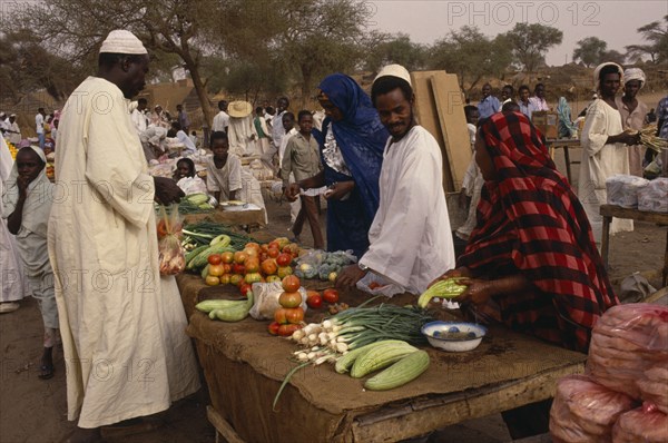 SUDAN, North Darfur, El Fasher, Fruit and vegetable stall at outside market with vendors and male customer.