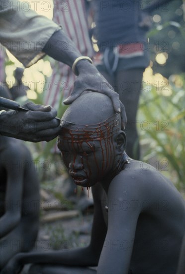 SUDAN, Tribal People, "Dinka initiation into manhood.  Scarring ceremony in which each boy has six horizontal lines cut into forehead, any sign of weakness brings dishonour."