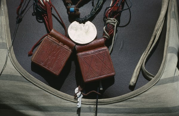SUDAN, Mornei Settlement, Close view of leather pouches containing verses of the Koran worn around the neck as a charm by Chadian refugee woman together with old French coin and beads.