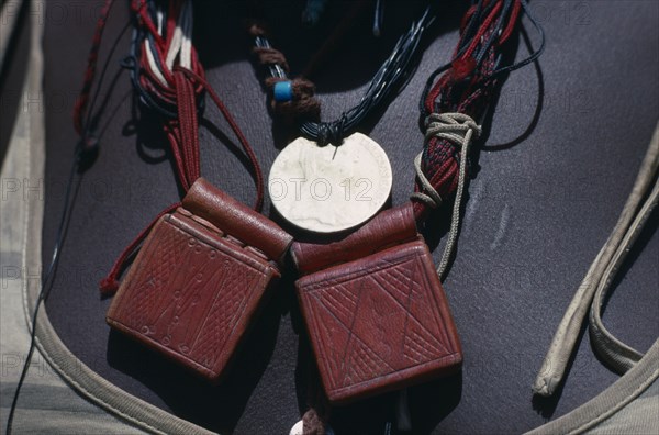 SUDAN, Mornei Settlement, Close view of leather pouches containing verses of the Koran worn as a charm around the neck by Chadian refugee woman together with old French coin and beads.