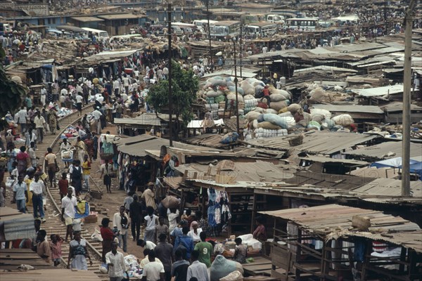 GHANA, Ashanti Region, Kumasi, "Busy market square with traffic, crowds of people and tin roofed open sided stalls."