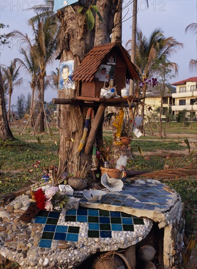 THAILAND, Andaman Sea, Takua Pa district, "Khao Lak, A memorial for those lost in the Tsunami, photographs, flowers, drinks and others objects placed around a tree."