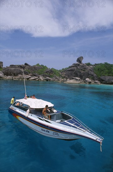 THAILAND, Similan Islands, Ko Bangu, People on board a small motor boat near the rocky shore.