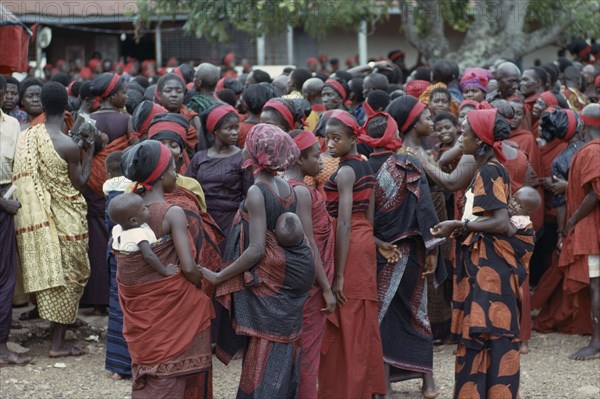 GHANA, Tribal People, "Group of women carrying babies on their backs at Ashanti funeral, dressed in red the colour of mourning.  Large mixed crowd in background."