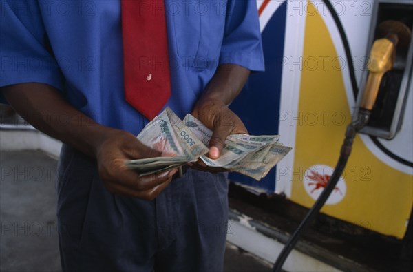 GHANA, Money, Ghanaian currency.  Counting cedi bank notes at a petrol station.