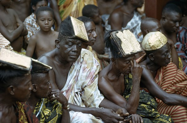 GHANA, Tribal People, Ashanti elders wearing traditional headdresses decorated with gold at tribal meeting.