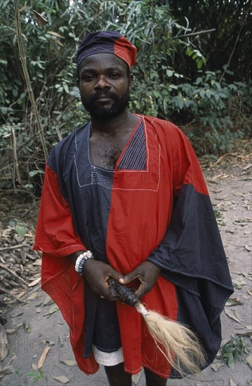 GHANA, Tribal People, Portrait of traditional priest and healer in village near Accra wearing black and red robes.