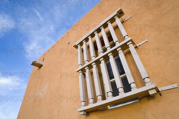 USA, New Mexico, Santa Fe, Wooden barred window on the side of an adobe style Pueblo Revival building