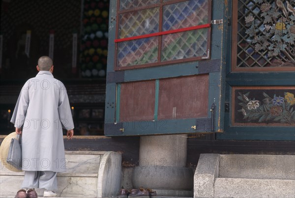 SOUTH KOREA, Seoul, Jogyesa Temple. A Nun walking up the steps to the temple sanctuary