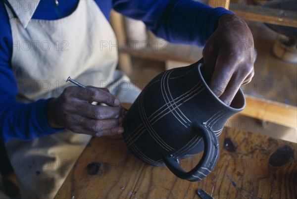 MALAWI, Dedza, Dedza Potteries producing Fair Trade goods for export. Craftsman decorating pot.