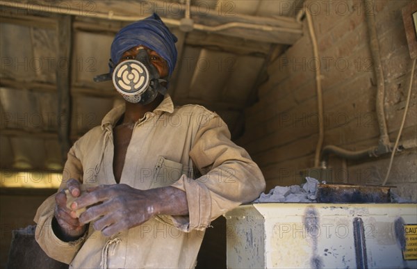 MALAWI, Dedza, Dedza Potteries producing Fair Trade goods for export.  Craftsman wearing protective mask and overalls to grind rock.