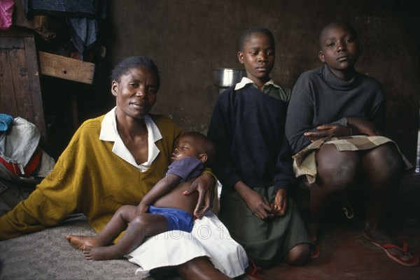 KENYA, Nairobi, "Korogocho slum area.  Margaret with two of her children and her fourteen year old servant girl Eppy on the right.  Like many girls, Eppy works for her keep."