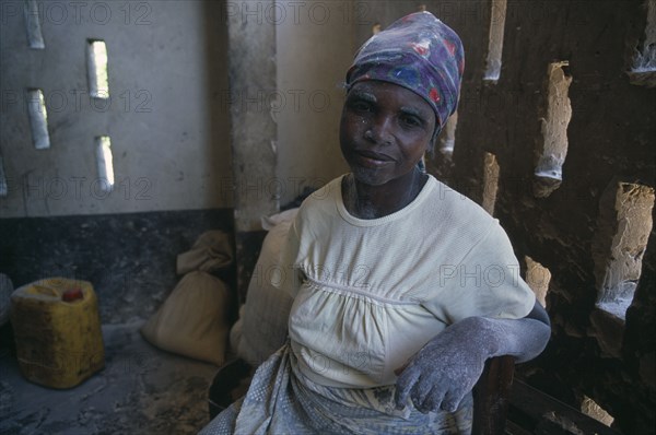 ZAMBIA, Mayukwayukwa Camp, Woman working in maize mill in camp for Angolan refugees with dust from maize flour on her face and hands.