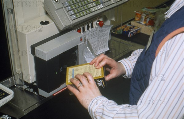 ENGLAND, Shopping, Staff using bar code price reader at supermarket checkout.