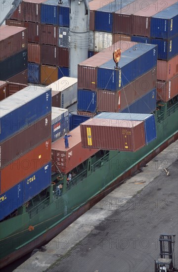 IVORY COAST, San Pédro, Containers being unloaded from vessel docked at San Pédro port.  Worker standing on container to direct crane.