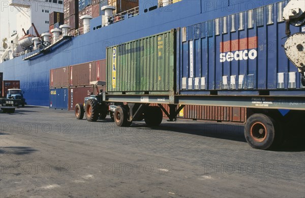 IVORY COAST, Abidjan, Container vessel docked at Abidjan port with tractor pulling trailer loaded with containers in foreground.