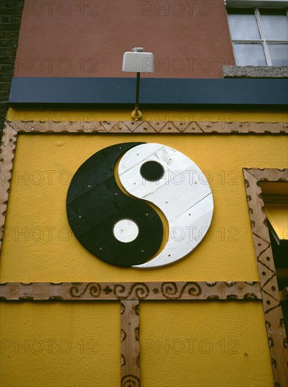 IRELAND, Dublin, "Yin and Yang symbol painted onto a wall. Yin Yang originates in ancient Chinese philosophy and metaphysics, which describes two primal opposing but complementary forces found in all things in the universe. Yin, the darker element, is passive, dark, feminine, downward-seeking, and corresponds to the night; yang, the brighter element, is active, light, masculine, upward-seeking and corresponds to the day; yin is often symbolized by water, while yang is symbolized by fire"