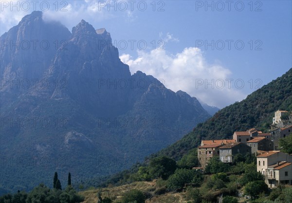 FRANCE, Corsica, The cusp shaped summit of Capo D’Orto provides a dramatic backdrop to the hillside village of Ota
