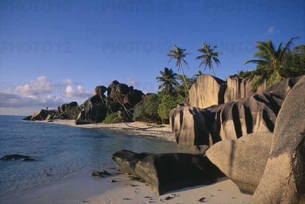 SEYCHELLES, La Digue , Anse Source D Argent, Rock formations along the coast with palm trees and green vegetation and turquoise sea