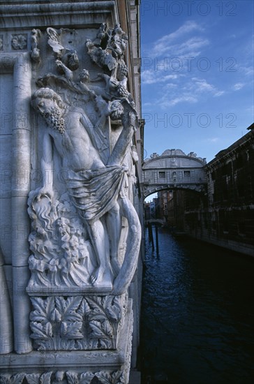 ITALY, Veneto, Venice, The Doges Palace. Relief carving of The Drunkenness of Noah or The Vine Angle on the corner of building beside The Bridge of Sighs with water below