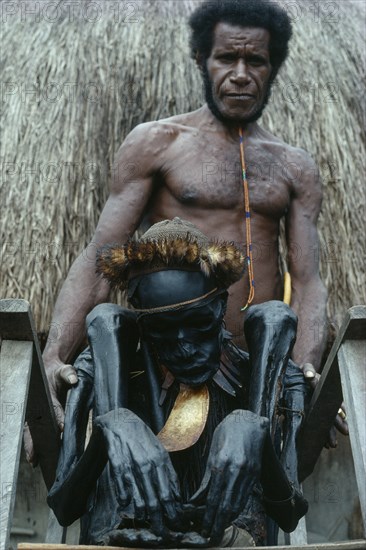 INDONESIA, Irian Jaya, Baliem Valley, "Jiwika Village. Dani Warrior man holding smoked ancestral mummy of Chief Weraper Elosarek. Irian Jaya was annexed by Indonesia in 1963 and is seeking independence, its situation remains unclear"