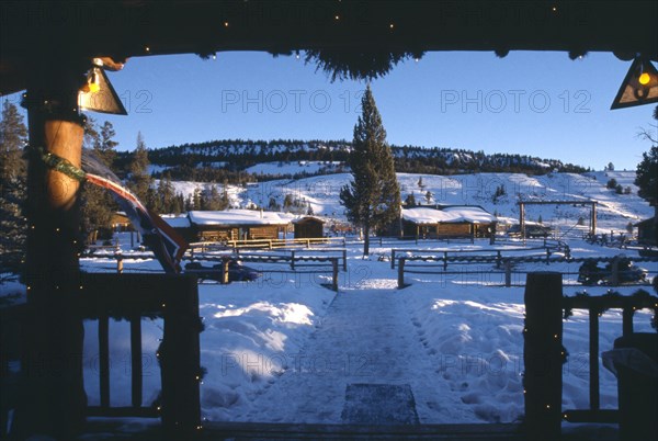 USA, Wyoming, Dubois, View of Guest cabins at the Triangle C Dude Ranch in the snow from building framed with Christmas lights