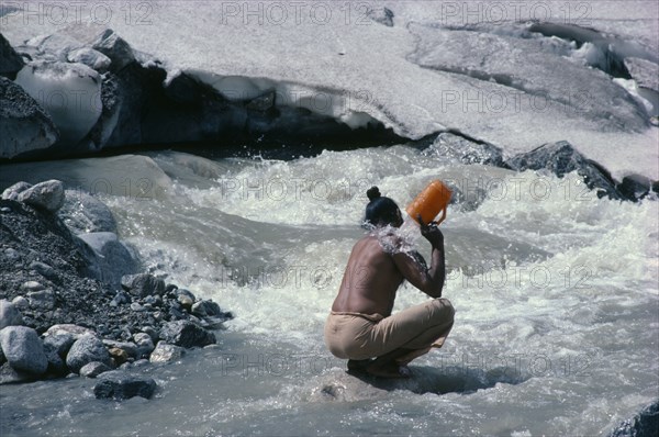 INDIA, Uttar Pradesh, Garwhal Region, "Sadhu pilgrim bathing at Gaumukh or the cow’s mouth, sacred source of the River Ganges."