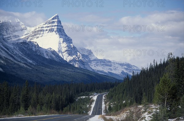 CANADA, Alberta, Banff National Park, Trans-Canada highway through mountain landscape with pine forests and melting snow.