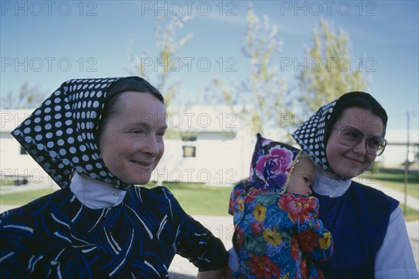 CANADA, Alberta, Hutterite women and child from the Milford farming colony near Raymond.  Hutterites are a communal branch of Anabaptists forming male dominated rural colonies.