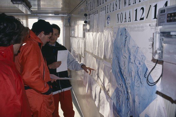 ANTARCTICA, Ross Sea,  Terra Nova Bay, Station of Italian Antarctica Progamme. Interior with people pointing towards a map on the wall
