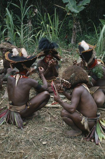 PACIFIC ISLANDS, Melanesia, Papua New Guinea, Southern Highlands.Tari. Huli Tribemen painting faces for Sing Sing Festival.