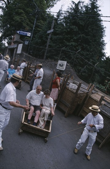 PORTUGAL, Madeira, Monte , Tourists starting their Toboggan ride down to Funchal guided by two drivers