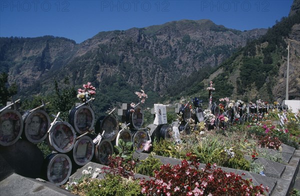 PORTUGAL, Madeira, Camara de Lobos, Curral das Freiras. Photographs of the dead with flowers outside the Church of Senhora do Livramento which are removed after five years