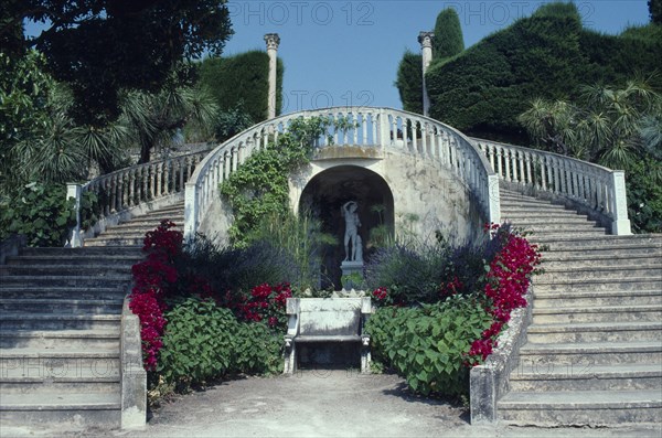 FRANCE, Provence Cote d Azur, Antibes, Musee Ile de France garden with steps surrounding a bench next to flowers and a statue