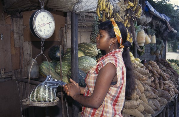 DOMINICAN REPUBLIC, Produce, Young woman weighing bag of produce at roadside fruit and vegetable stall.