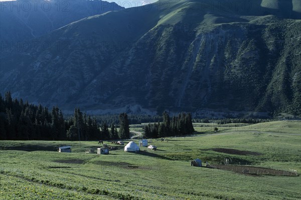 KIRGHIZSTAN, Tyan Shan, Horses grazing next to small huts on the mountain range.