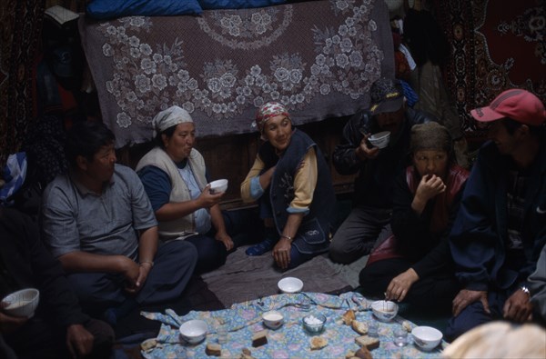 KIRGHIZSTAN, Workers, "Shepherds inside a yurt, eating and drinking, large rugs hanging on the walls"