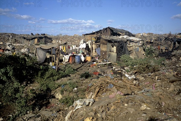 NICARAGUA, Managua Province, Managua, "The 'waste basket of Chureca' has existed since the late 1960's in the Acahualinca district of Managua, Nicaragua. It covers 42 hectares, is bombarded with thousands of tonnes of waste a day and is home to over 170 struggling families. By day over 1500 more Nicaraguans arrive at the site, some of whom are children who have been sent by their parents, others come by their own initiative. All compete with the adults to find, harvest and re-sell recyclable material. Of the minors who go to the waste basket - 88% it has respiratory problems, 62% suffer from parasites and 42% have serious skin diseases. Although the sky is clear and blue the air is thick of burning waste or rotting waste. Little houses or 'casitas' lie in a mixed muddle of rubbish and waste. The house at the front of shot is made up of an eclectic collection of doors, wooden planks, dustbin bags, hanging bits of ripped tarpaulin, corrugated iron strips and whatever waste material seems...