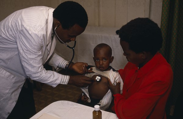KENYA, Nairobi, Doctor listening to chest of child in clinic in Kariobangi slum area.