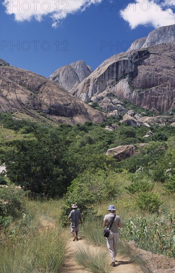 MADAGASCAR, Ambalavao, A tourist being lead by a guide towards rocky mountains and trees in the Anjaha Nature Reserve